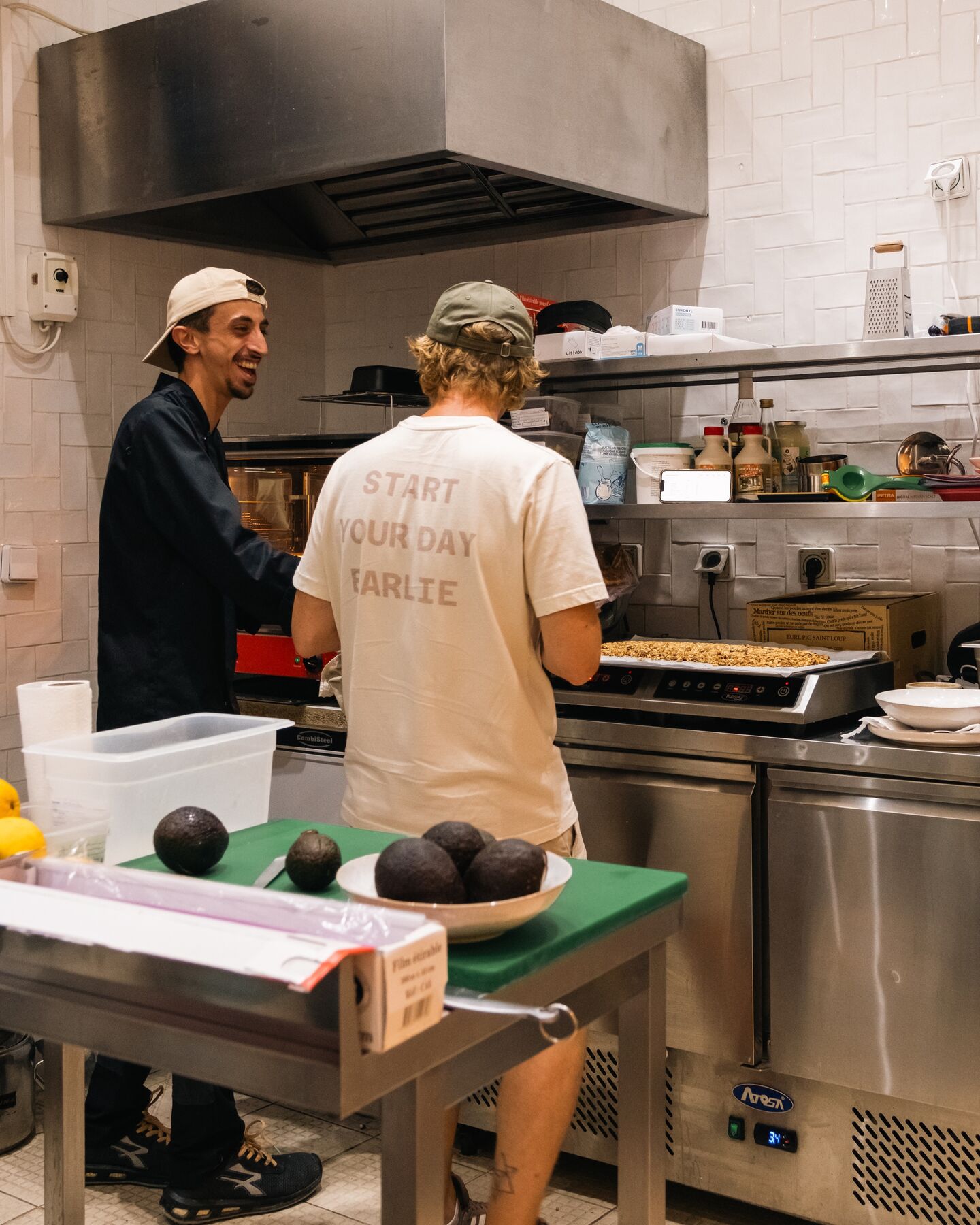 Deux membres de l'équipe en cuisine, devant les plaques et le plan de travail.